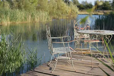 a table and chairs sitting on a dock next to the water at Grande Maison de Charme a 5 mn du centre ville in Narbonne