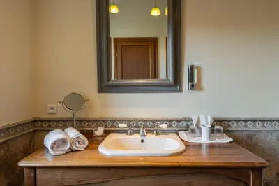 a bathroom with a sink and a mirror and towels at Grande Maison de Charme a 5 mn du centre ville in Narbonne