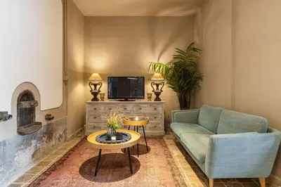 a living room with a couch and a tv and a table at Grande Maison de Charme a 5 mn du centre ville in Narbonne