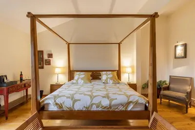 a bedroom with a canopy bed and a chair at Grande Maison de Charme a 5 mn du centre ville in Narbonne