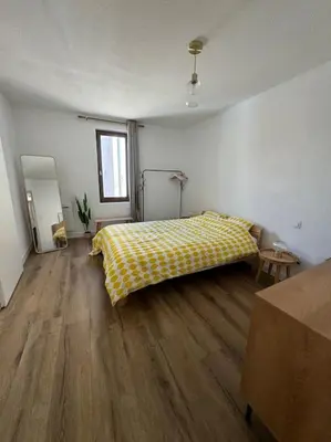 a bedroom with a bed with a yellow blanket on a wooden floor at Appartement centre historique in Narbonne