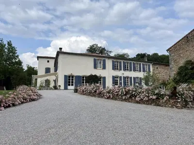 a large white house with pink flowers in the driveway at Domaine de la laugerie - relais du consul in Castres