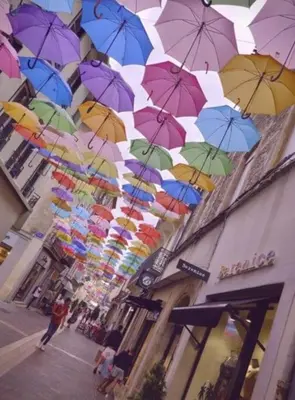 a bunch of colorful umbrellas hanging from a building at Dame Carcas in Carcassonne