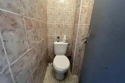 a bathroom with a toilet and a tiled wall at Spacious nest with sea view in Port-la-Nouvelle