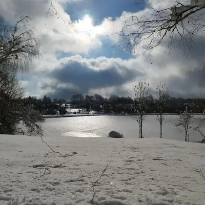 a snow covered field with a body of water at Chaleureux Chalet Lac Roussinas in Anglès