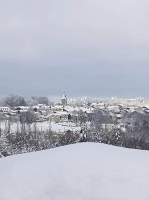 a snow covered field with a city in the background at Chaleureux Chalet Lac Roussinas in Anglès