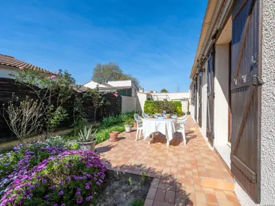 a patio with a table and chairs and flowers at Holiday Home La maison du carignan by Interhome in Armissan
