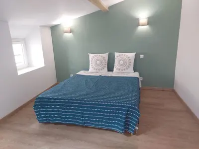 a bedroom with a bed with a blue and white comforter at Le duplex sigeannais in Sigean