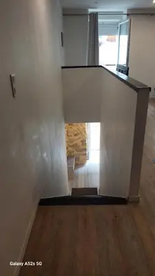 a white staircase in a room with a wooden floor at Le duplex sigeannais in Sigean