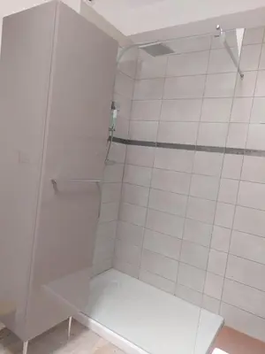 a shower with a glass door with a bench in it at Le duplex sigeannais in Sigean