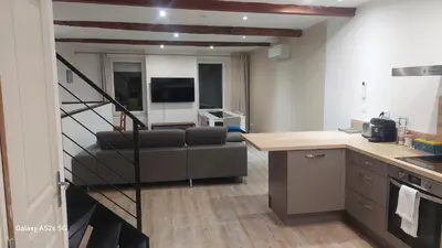 a kitchen and a living room with a couch and a staircase at Le duplex sigeannais in Sigean