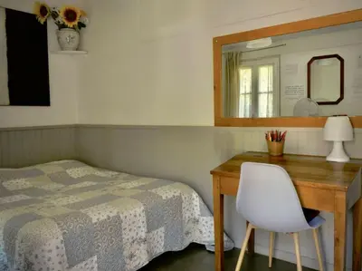 a bedroom with a bed and a desk with a mirror at La campagne dans la ville in Narbonne