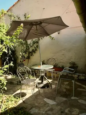 a table and chairs with an umbrella on a patio at La campagne dans la ville in Narbonne