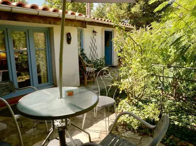 a patio with a table and chairs and an umbrella at La campagne dans la ville in Narbonne