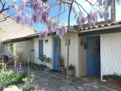 a house with a blue door and purple flowers at La campagne dans la ville in Narbonne