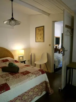 a bedroom with a bed and a chair and a door at La campagne dans la ville in Narbonne