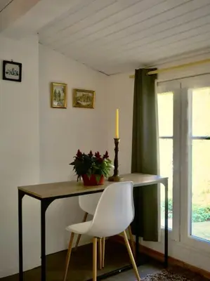 a dining room table with a candle and a white chair at La campagne dans la ville in Narbonne