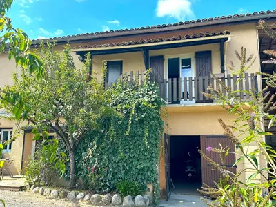 a house with a balcony and a tree at Gîte Tintinnabule in Ventenac