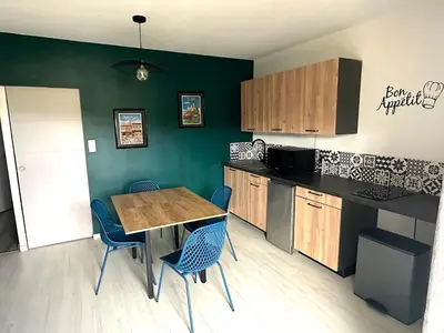 a kitchen with a wooden table and blue chairs at Gîte Tintinnabule in Ventenac
