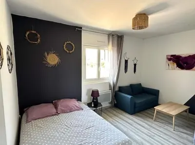 a bedroom with a bed and a blue chair at Gîte Tintinnabule in Ventenac