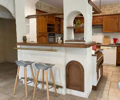 a kitchen with two stools and a counter with an oven at Maison avec 2 appartements, jacuzzi et accès privé à la rivière in Ladern-sur-Lauquet