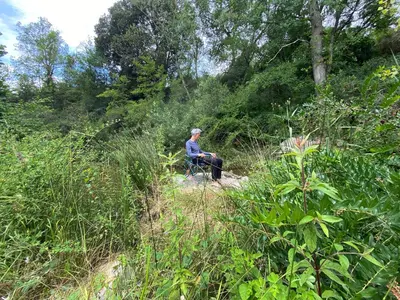 a person sitting in a chair in the woods at Maison avec 2 appartements, jacuzzi et accès privé à la rivière in Ladern-sur-Lauquet
