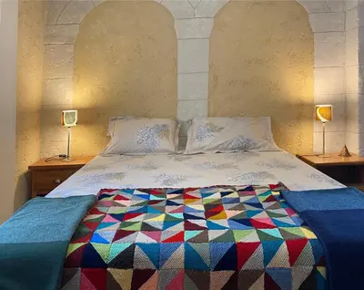 a bedroom with a bed with a colorful quilt on it at Maison avec 2 appartements, jacuzzi et accès privé à la rivière in Ladern-sur-Lauquet