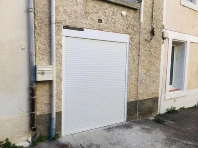 a white garage door on the side of a building at La Barbacane in Lapalme