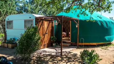 a blue and green trailer with a wooden door at Les Cabanes d'ErbeFol in Ansignan