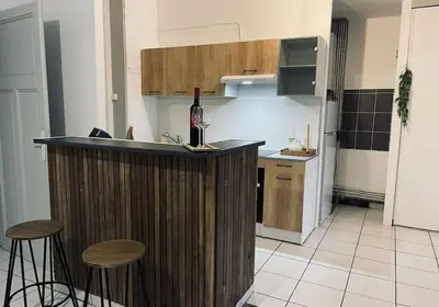 a kitchen with a bar with stools and a bottle of wine at Appartement 3 chambres proche centre ville in Carcassonne