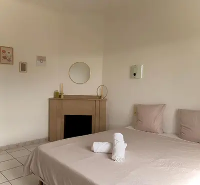 a bedroom with a bed with white sheets and a fireplace at Appartement 3 chambres proche centre ville in Carcassonne