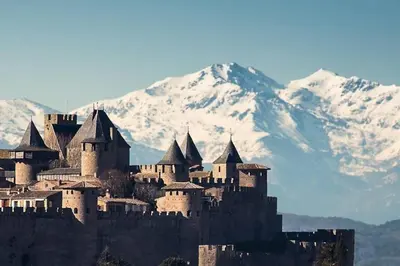 a large castle with snow covered mountains in the background at Appartement 3 chambres proche centre ville in Carcassonne