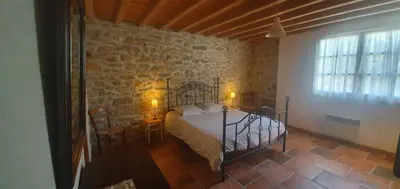 a bedroom with a bed and a stone wall at Le Clos Sainte Marie - Lampy in Cenne-Monestiès