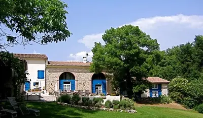 a stone house with blue doors and a yard at Le Clos Sainte Marie - Caune in Cenne-Monestiès