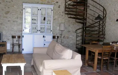 a living room with a white couch and a spiral staircase at Le Clos Sainte Marie - Caune in Cenne-Monestiès