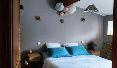 a bedroom with a bed with blue pillows at Les jardins du Canal in Sainte-Eulalie