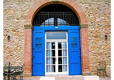 a blue door in a stone building with two chairs at Le Clos sainte Marie - Crouzette in Cenne-Monestiès