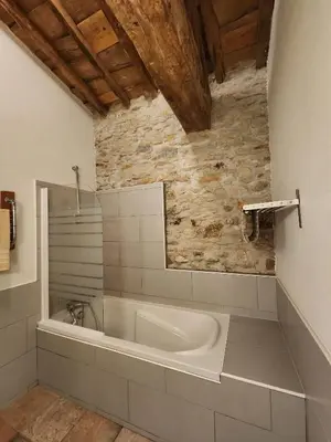 a bath tub in a bathroom with a stone wall at Le Clos sainte Marie - Crouzette in Cenne-Monestiès