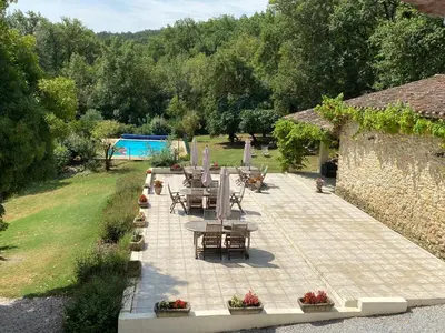 a patio with tables and chairs in a garden at Le Clos sainte Marie - Crouzette in Cenne-Monestiès