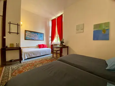 a bedroom with two beds and a window with red curtains at Maison d'hôtes La Giraudasse in Soulatgé