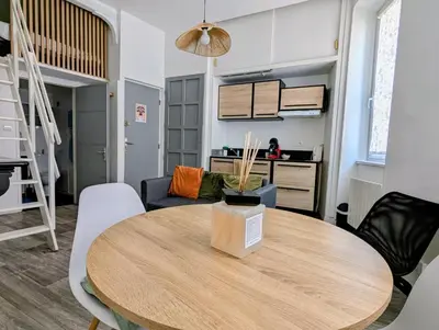 a dining room and living room with a table and chairs at Escapade cœur de ville Narbonne in Narbonne
