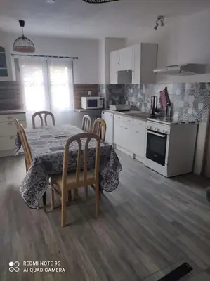a kitchen with a table and chairs and a kitchen with white cabinets at gite 4 pers a ROUZE in Rouze