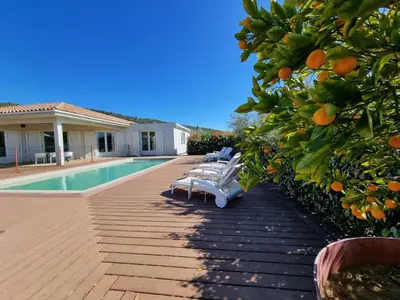 a pool with chairs and an orange tree next to a house at Le Ranch in Oupia