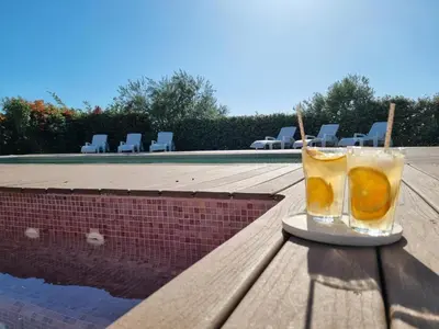 a glass of orange juice sitting on a table next to a pool at Le Ranch in Oupia