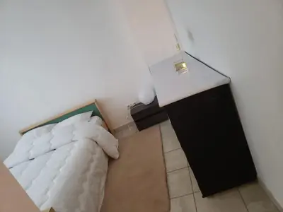 a bedroom with a white bed and a black cabinet at Maison meublée avec garage in Pamiers