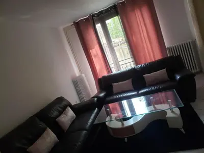 a living room with a black couch and a glass table at Maison meublée avec garage in Pamiers