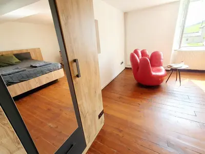 a room with a red chair and a bed at La ferme - Domaine Monbel in Mirepoix