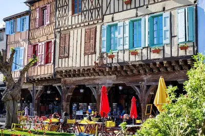 a building with tables and umbrellas in front of it at La ferme - Domaine Monbel in Mirepoix