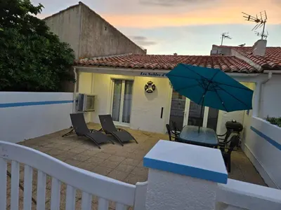 a patio with a table and chairs and an umbrella at Les sables d'or in Port-la-Nouvelle