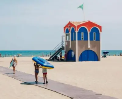 a couple of people walking on the beach with a surfboard at Les sables d'or in Port-la-Nouvelle
